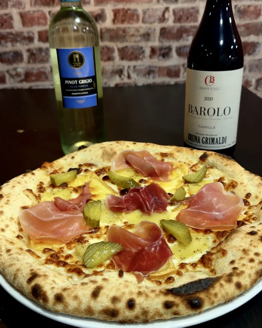 Pizza du mois d'octobre Casa Gianotti : base crème et mozzarella, raclette fondue, jambon cru et cornichons, pâte napolitaine cuite au feu de bois
